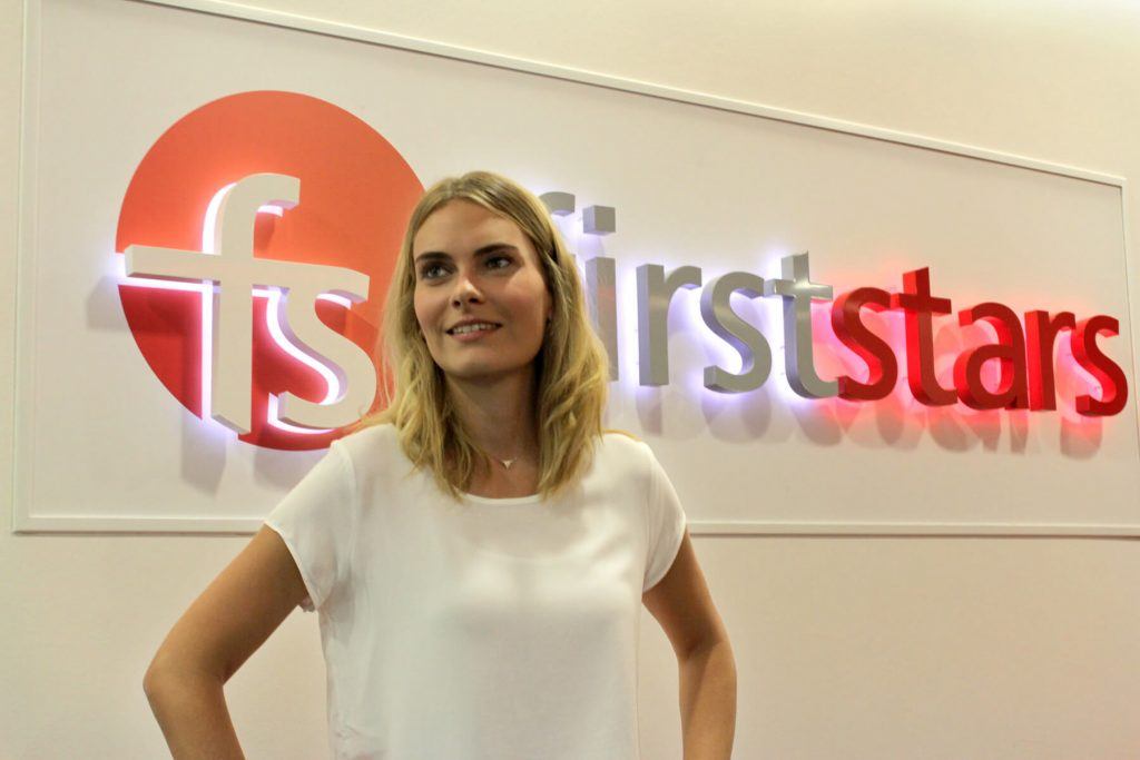 Digitale Leute - Anne Gradler - firststars - Anne posiert vor dem Logo der SEA-Agentur.