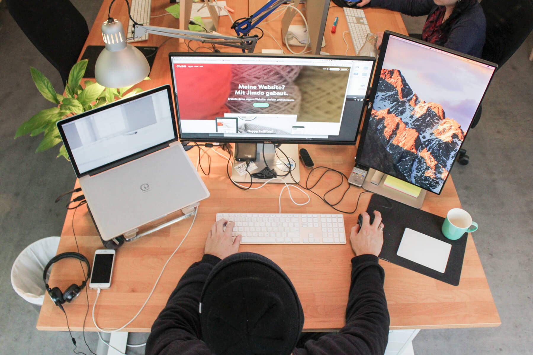 Ingo Ellerbusch - Jimdo - Ingos Arbeitsplatz von open: Sein MacBook Pro, ein 27 Zoll Monitor und ein vertikaler, für den Code. Dazu Tastatur und Maus.